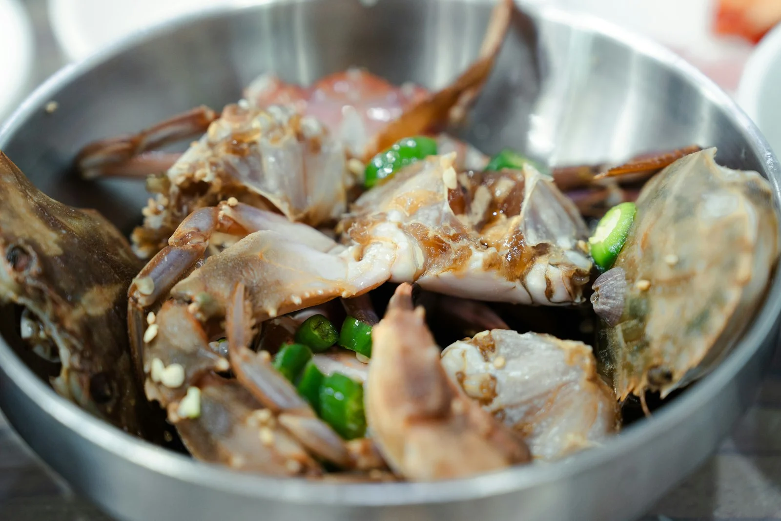 Marinated raw crab with green chilli in a metal bowl